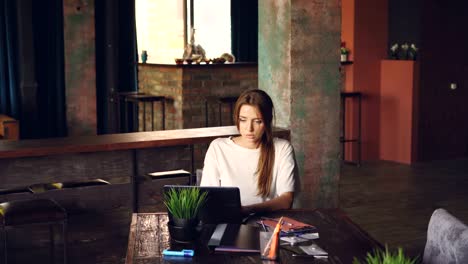 Cheerful-girl-office-worker-is-working-at-desk-while-her-coworkers-are-bringing-birthday-cake-and-putting-party-hat-on-her,-young-woman-is-clapping-hands.