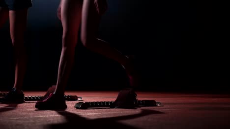 Three-girls-in-black-clothes-are-in-the-starting-pads-to-start-the-race-in-the-competition