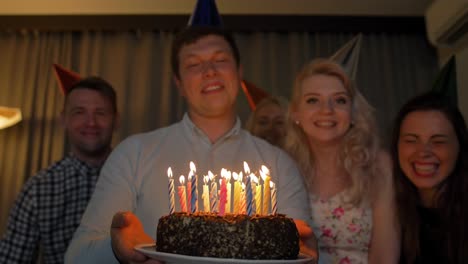 Happy-guy-with-friends-bringing-birthday-cake-to-You