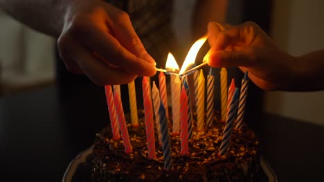 Woman-and-man-lights-candles-on-tasty-birthday-cake.-Prepearing-for-party