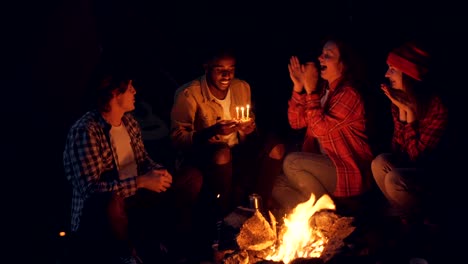 Grupo-multiétnico-de-jóvenes-turistas-es-felicitar-al-hombre-del-afroamericano-por-darle-la-torta-de-cumpleaños-y-palmas-de-las-manos,-es-soplar-velas-y-morder-el-pastel.