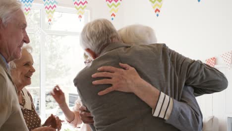 Happy-Senior-Woman-Greeting-Guests-at-Home