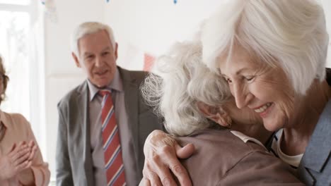 Senior-Freundinnen-umarmen-auf-Geburtstagsparty