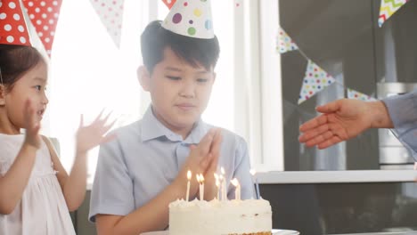 Niña-ayudando-hermano-soplar-las-velas-sobre-el-pastel