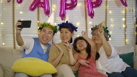 Portrait-of-young-asian-family-relaxing-and-taking-selfie-photo-on-sofa-at-home.-Happy-family-enjoying-time-together.