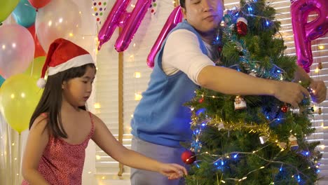 Asian-Vater-und-Tochter-schmücken-den-Weihnachtsbaum-in-Zeitlupe