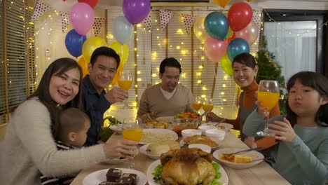 Happy-Asian-family-making-video-call-and-enjoying-christmas-dinner-together-at-home.