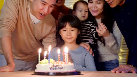Little-girl-blows-out-candles-on-birthday-cake-at-party-with-happy-emotion.-People-with-party-and-celebration-concept.-4K-Resolution.