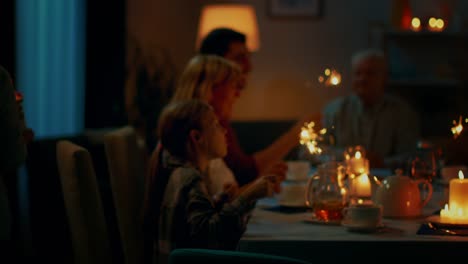 Following-Shot-of-a-Daughter-Bringing-Birtday-Cake-with-Candlelights-to-Her-Senior-Father.-Family-Dinner-and-Celebration,-People-Gathered-at-the-Evening-Dinner-Table.