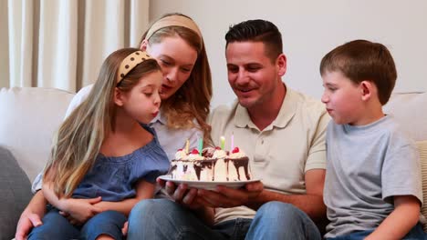 Happy-young-family-sitting-on-sofa-celebrating-a-birthday