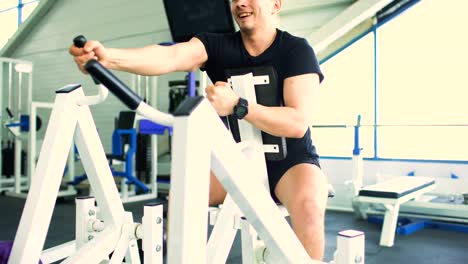 Handsome-sporty-man-is-exercising-and-smiling-in-fitness-club-and-gym-center