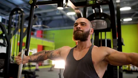 Guapo-hombre-deportivo-está-haciendo-ejercicio-mirando-a-la-cámara-en-el-club-de-fitness