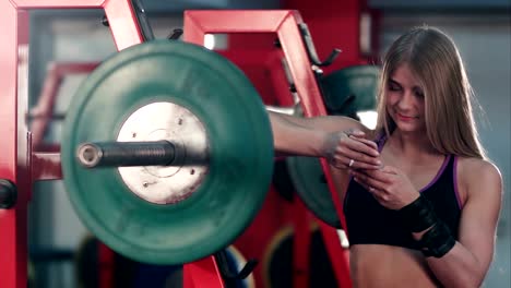 Sonriente-mujer-atlética-mensajes-en-su-teléfono-en-el-gimnasio