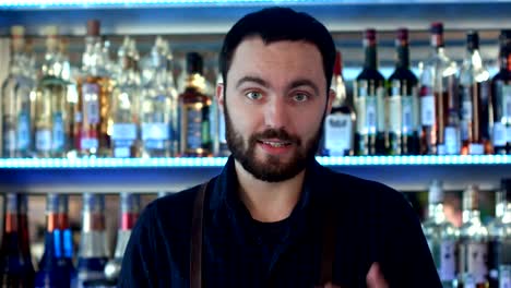 Positive-bartender-talking-to-a-camera-at-a-bar-counter