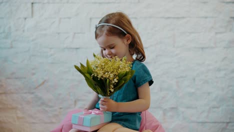 cute-little-girl-shows-flowers-and-a-gift