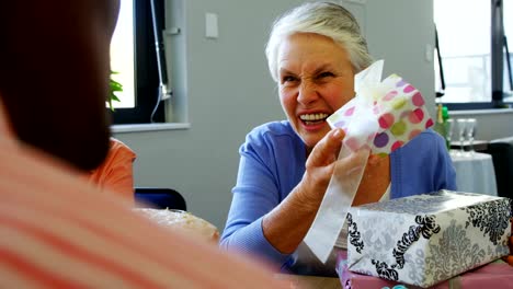 Senior-woman-holding-gift-box-and-interacting-with-friends-4k