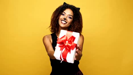 Young-african-woman-cat-with-pretty-make-up-calling-you-and-giving-present-isolated-over-yellow