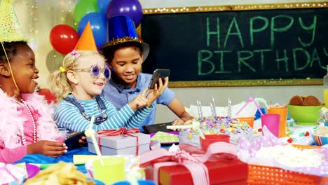 Kinder-betrachten-Bilder-im-Handy-während-Geburtstag-party-4k