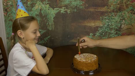 Mädchen-mit-den-Händen-klatschten.-Sitzendes-Mädchen-Angst-vor-Feuer.-Funkelnde-Feuer-Brunnen-in-einen-Kuchen.-Mädchen-Geburtstag.-Kuchen-mit-Lichtern.-Mans-Hand-Feuer-mit-leichter-Feuer-Brunnen.