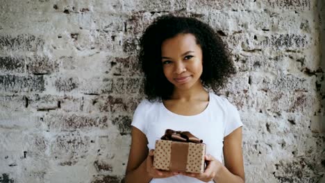 Porträt-des-jungen-glücklich-afrikanisches-Mädchen-Geschenkbox-halten-und-Lächeln-in-die-Kamera