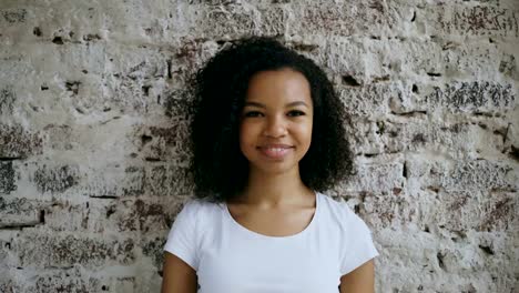 Portrait-of-curly-african-american-girl-present-gift-box-and-smiling-into-camera