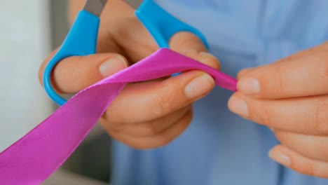 Close-up-shot-of-woman-cutting-ribbon-of-wedding-bouquet-at-workshop