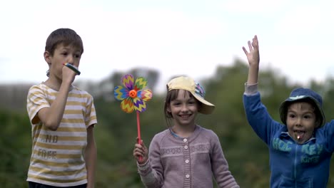 Three-children-look-at-the-camera-and-are-very-happy,-festive-mood,-birthday,-laughing-and-smiling-on-nature