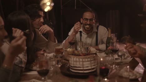 Multi-ethnic-friends-eating-gourmet-birthday-cake-at-rustic-dinner-party