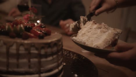 Close-up-of-woman-cutting-slices-of-gourmet-cake-at-dinner