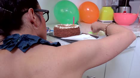 Mujer-de-decorar-torta-con-velas-sobre-la-mesa-en-la-cocina