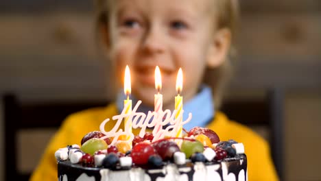 Close-up-of-boy-blowing-candles-on-birthday-cake