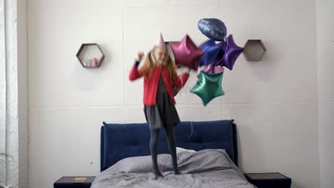 Teen-girl-jumping-on-bed-with-baloons-on-birthday