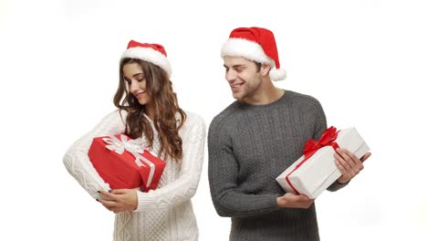 4k-young-couple-in-sweater-holding-present-and-treat-like-a-child-on-white-background.