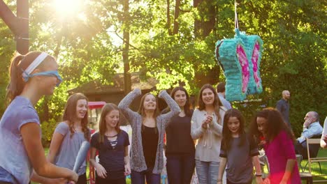 Freunde-sehen-Sie-pre-teen-Mädchen-schlagen-eine-Piñata-zum-Geburtstag