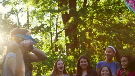 Girls-watch-their-friend-hitting-a-piñata-on-her-birthday