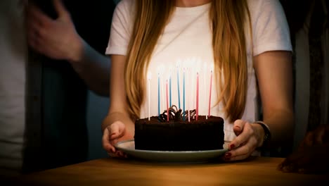 People-dancing-around-birthday-cake-with-candles.-Friends-celebrate-together.-Girl-in-white-shirt-holds-a-pie.-Party.-4K
