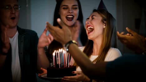 Beautiful-woman-makes-a-wish-and-blows-on-candles.-Diverse-multi-ethnic-group-celebrate-birthday-party-together.-4K