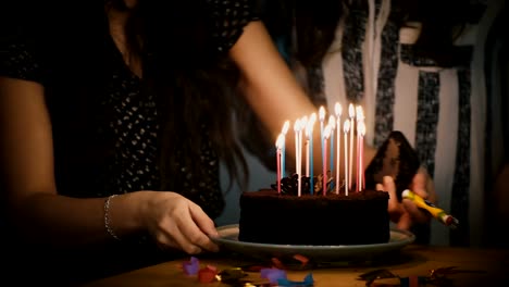 Dos-chicas-preparan-pastel-de-cumpleaños-con-velas.-Celebración-de-la-fiesta-de-sorpresa.-Amigos-juntos.-Ambiente-festivo-unidad-4K