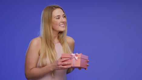 Hands-are-giving-a-gift-box-to-a-stunning-beautiful-young-Woman-and-she-is-pleased