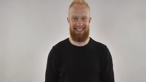 A-guy-with-a-red-beard-is-smiling,-holding-a-red-gift