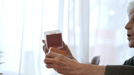 Senior-Woman-Eröffnung-Geschenkbox-zum-Zeitpunkt