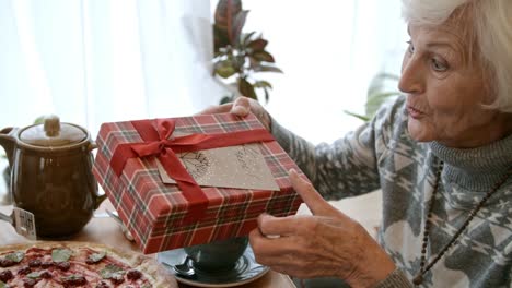 Senior-Lady-genießen-Geschenk-beim-Abendessen-im-Restaurant