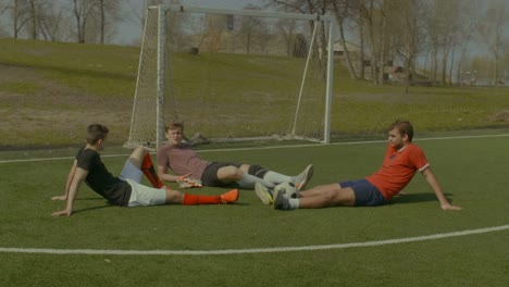 Footballers-relaxing-on-soccer-field-after-game