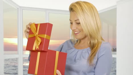 Woman-receiving-gift-in-red-box-on-window-background-with-evening-sunset-in-sea