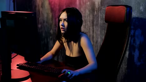 Serious-woman-enjoys-victory-in-a-video-game.-Gamer-girl-playing-online-game-on-a-pc-computer-wearing-headset-and-talking-with-a-team-using-microphone