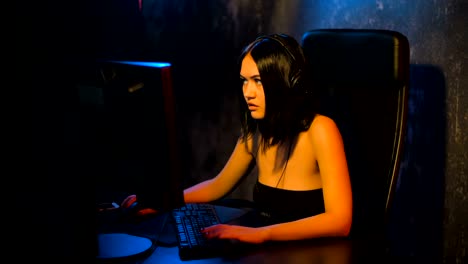 Serious-woman-gamer-playing-online-game-on-a-pc-computer-wearing-headset-and-talking-with-a-team-using-microphone