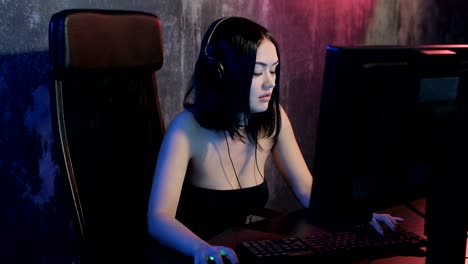 Serious-woman-gamer-playing-online-game-on-a-pc-computer-wearing-headset-and-talking-with-a-team-using-microphone