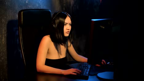 Serious-woman-gamer-playing-online-game-on-a-pc-computer-wearing-headset-and-talking-with-a-team-using-microphone