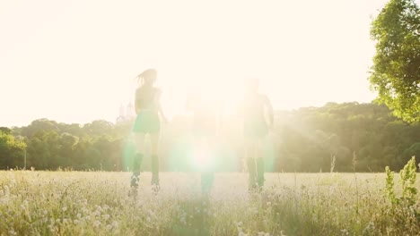 Tres-chicas-en-botas-con-resortes-corriendo-por-el-parque-de-verano-al-atardecer-haciendo-deportes