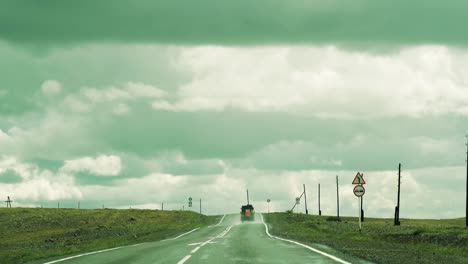 a-loaded-car-is-driving-down-the-road-in-the-mountains.-Rain-and-overhanging-clouds